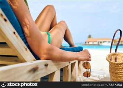 Young woman at beach on wooden sun bed loungers. Summer vacation at Maldives.