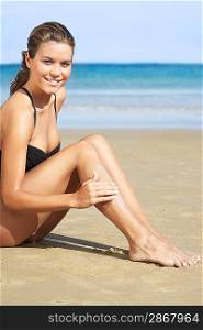 Young Woman at Beach Putting Lotion on Legs