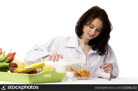 young woman at breakfast pouring milk. young woman at breakfast pouring milk in corn flakes