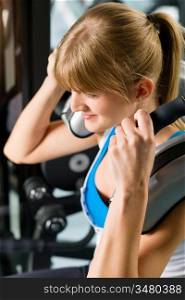 Young woman at gym exercise abdominal muscles on machine