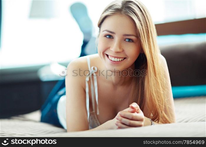 Young woman at home, lying and smiling