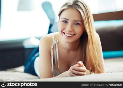 Young woman at home, lying and smiling