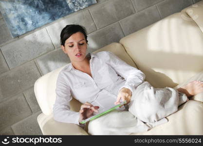 Young woman at home relaxing in her lliving room reading a digital tablet PC surf internet and work