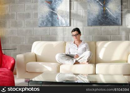 Young woman at home relaxing in her lliving room reading a digital tablet PC surf internet and work