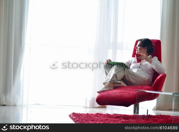 Young woman at home relaxing in her lliving room reading a digital tablet PC surf internet and work