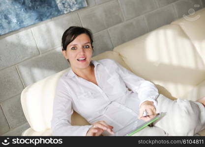 Young woman at home relaxing in her lliving room reading a digital tablet PC surf internet and work