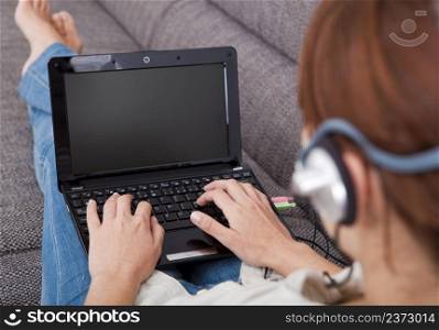 Young woman at home with a laptop and speaking over the internet, focus is on the laptop