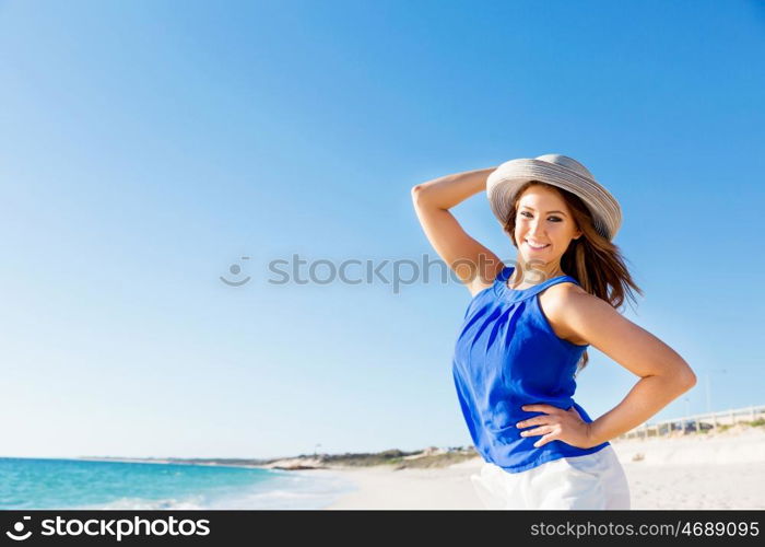 Young woman at the beach. Portrait of young pretty woman wearing hat at the beach