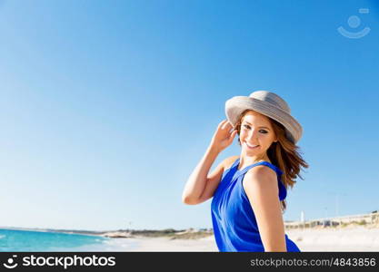 Young woman at the beach. Portrait of young pretty woman wearing hat at the beach