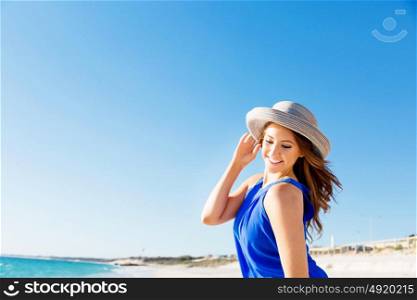 Young woman at the beach. Portrait of young pretty woman wearing hat at the beach