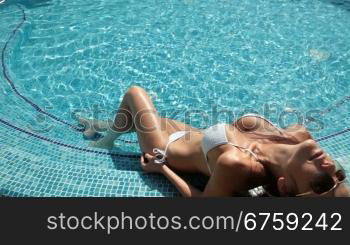 Young woman at the edge of swimming pool at summer resort