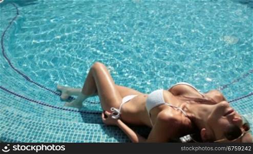 Young woman at the edge of swimming pool at summer resort