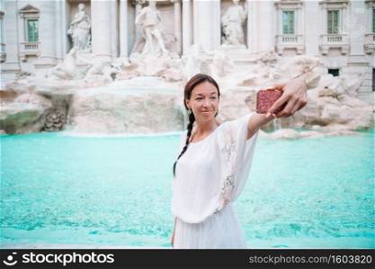 Young woman background of the Fountain of Trevi during her trip in Rome, Italy. Girl enjoy her european vacation. Pretty woman looking to the Fountain of Trevi during her trip in Rome, Italy. Girl enjoy her european vacation