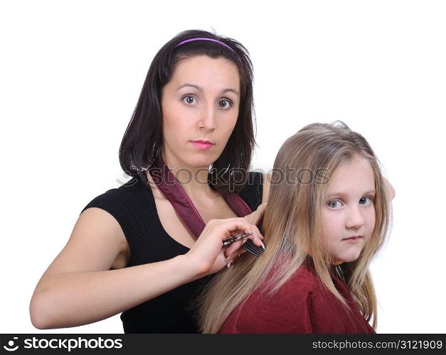 Young woman barber makes hairstyle for a girl isolated on white background