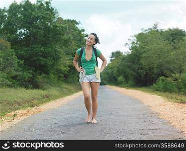 Young woman barefoot walking rural road smiling