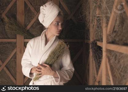 young woman bathrobe holding medical herbs