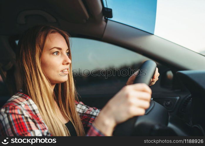 Young woman beginner driving a car, back view. Female person in vehicle, automobile driver concept. Young woman beginner driving a car, back view