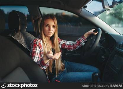 Young woman beginner offers a ride on car. Female person in vehicle, driving automobile concept. Young woman beginner offers a ride on car