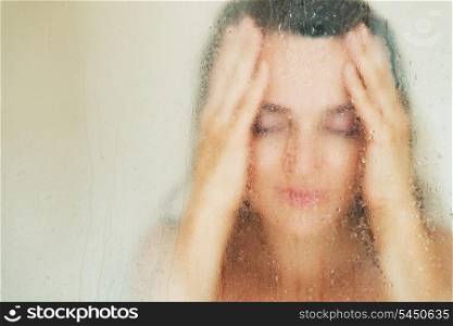 Young woman behind weeping glass shower door