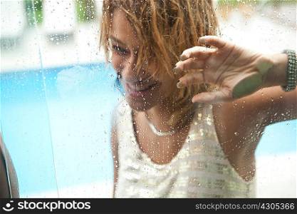 Young woman behind window of hotel swimming pool, Rio De Janeiro, Brazil