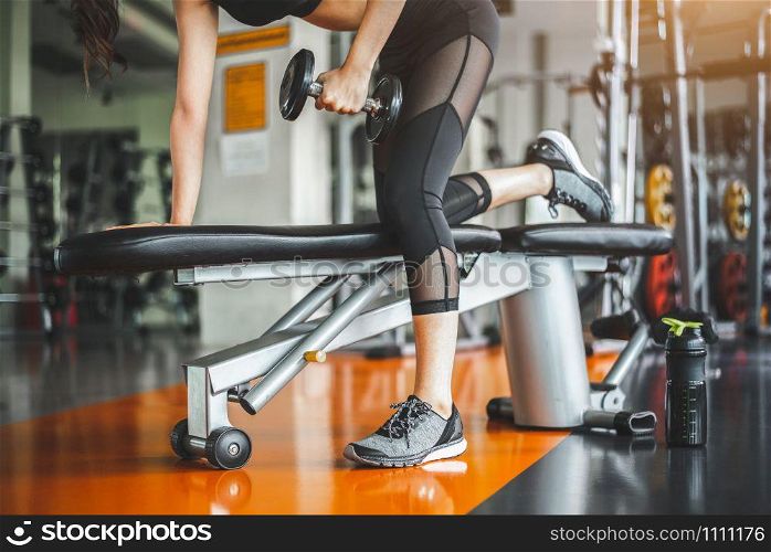 Young woman bench pressing with dumbbells in fitness gym. Working triceps and chest weight lifting. Sport and workout exercise muscle training. People lifestyle in sportwear. Bodybuilder active girl