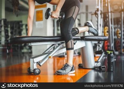 Young woman bench pressing with dumbbells in fitness gym. Working triceps and chest weight lifting. Sport and workout exercise muscle training. People lifestyle in sportwear. Bodybuilder active girl