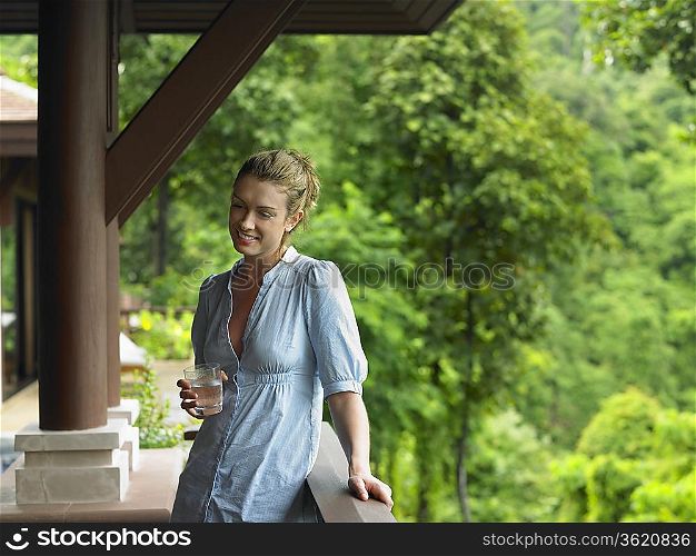 Young Woman Beneath Veranda with Glass of Water