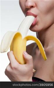 Young woman biting banana isolated on white