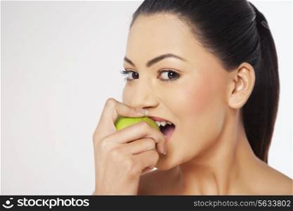 Young woman biting green apple