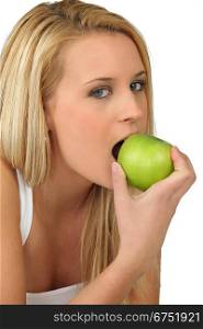 Young woman biting into a crisp green apple