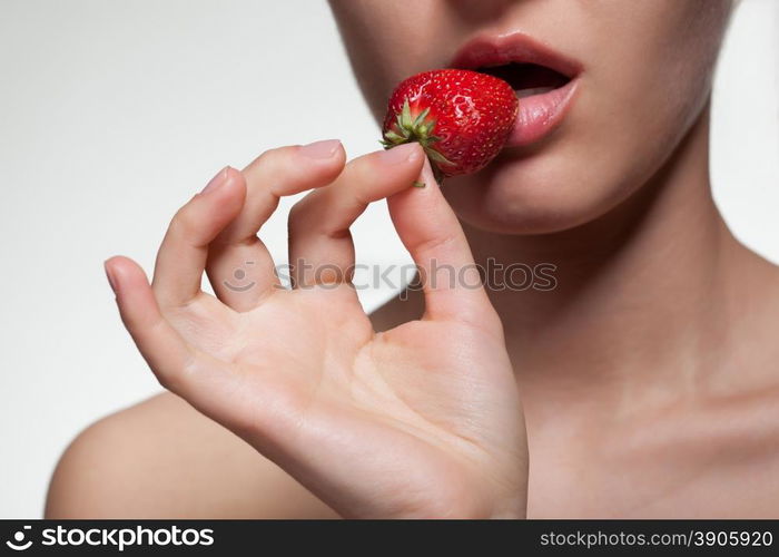 Young woman biting strawberry isolated on white