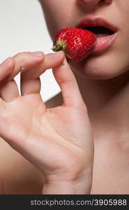 Young woman biting strawberry isolated on white