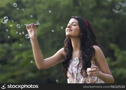 Young woman blowing bubbles in a park