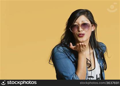 Young woman blowing kisses over colored background