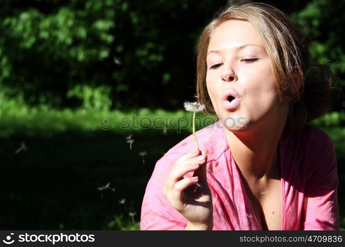 young woman blowing on the dandelion &#xA;