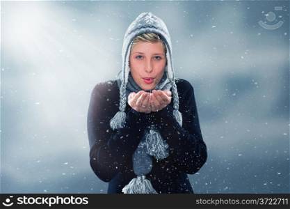 young woman blowing snow off her hands. young woman in winter blowing snow off her hands