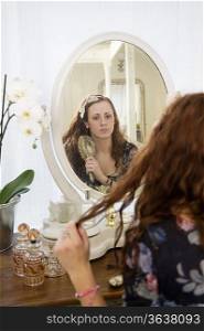Young woman brushing her hair in front of mirror