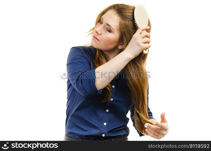 Young woman brushing long healthy brown hair, using hairbrush. Haircare.. Woman brushing long healthy brown hair