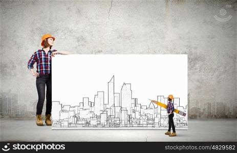 Young woman builder wearing helmet and holding banner with construction project. Development project