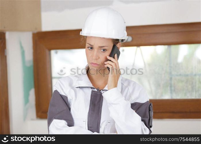 young woman builder with serious expression on the phone