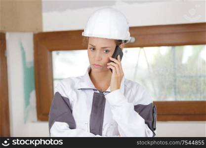 young woman builder with serious expression on the phone