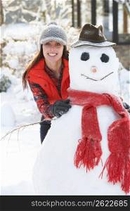Young Woman Building Snowman In Garden