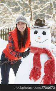 Young Woman Building Snowman In Garden