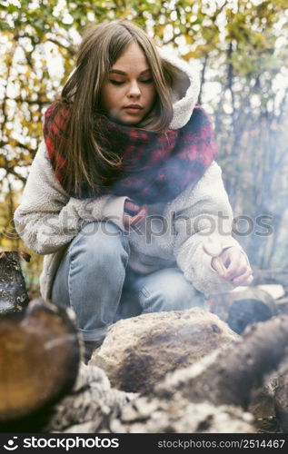 young woman burning marshmallows camp fire outdoors