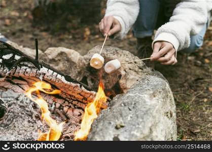 young woman burning marshmallows camp fire winter