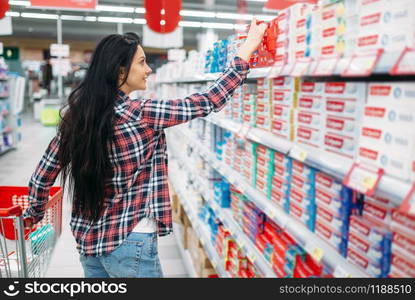 Young woman buying toothpaste in supermarket. Female customer on shopping in hypermarket, department of personal care products