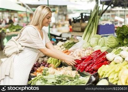 Young woman buying vegetables at the market