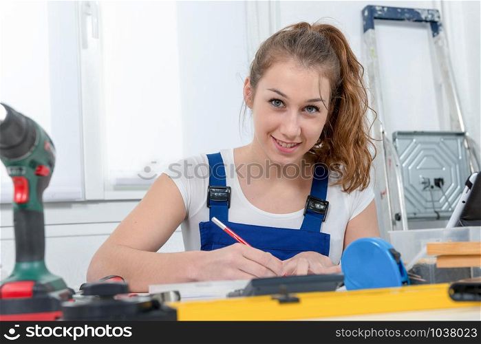 young woman carpenter sitting at desk in her workshop