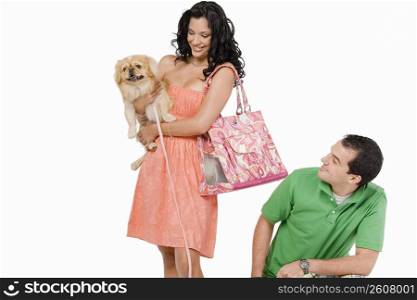 Young woman carrying a dog with a young man looking at her