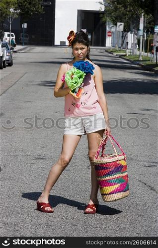 Young woman carrying bag standing in the middle of the street